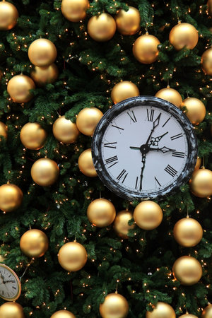 An old clock on a Christmas tree among golden baubles.