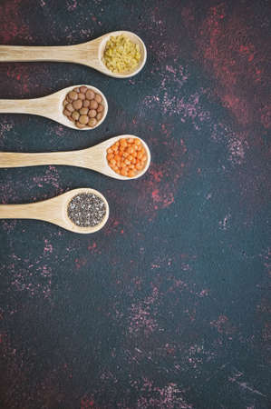 Different or various types of dry beans or dried legumes in wooden spoon on dark background. Whole grains, healthy food and diet concept. Top view. flat layの写真素材