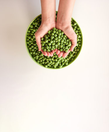 Close-up of a lot of ripe peas in hands, heart shaped. Green pea in a green bowl. Tasty and healthy food. Vegetablesの写真素材