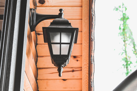 A wall of a log cabin with a black sconce lamp on the wallの写真素材
