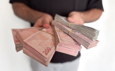 Hands holding numerous stacks of Turkish Lira banknotes, symbolizing wealth, savings, and financial transactions, cash flow, and economic dealingsの写真素材