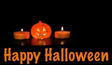 Halloween background with pumpkin and candles on black background. Copy space.の写真素材