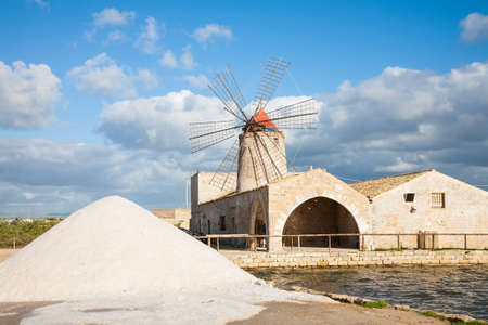 A salt pan windmill and heap of sea salt near Trapani in western Sicily, italyの写真素材