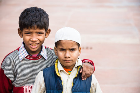 Agra, India - 2015, January 10 : Two young boys, one wearing a muslim taqiyah,  in the Jama Masjid mosque courtyard of Agra, Indiaのeditorial素材