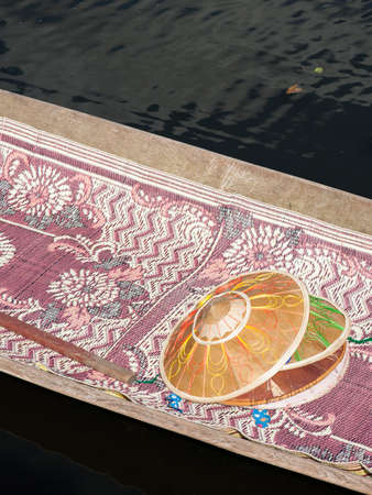 Some conical bamboo hats lying in a wooden boat on a colorful carpet, Inle Lake, Burmaの写真素材