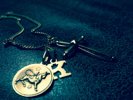 A necklace with three pendants: a letter k, a cross and the taurus zodiac signの写真素材