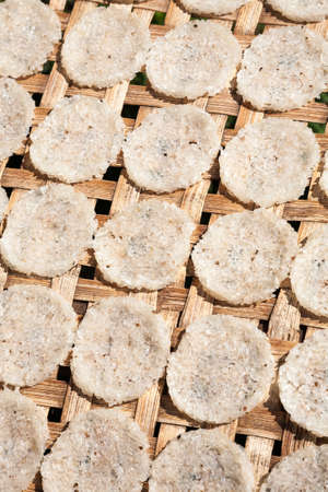 A number of compressed rice cakes or galettes on a rack outside drying under the sunの写真素材