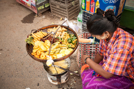 Yangon, Myanmar - 2017, January 8 : A woman frying vegetables in batter and selling them on the streets of Yangon in Burmaのeditorial素材