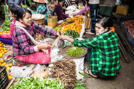 Nyaungshwe, Myanmar - 2017, January 4 : A female hawker or vendor selling tamarind to a female customer, both wearing thanaka cream, in a street market in the town of Nyaungshwe on the Inle Lake of central Burmaのeditorial素材