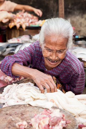 Yangon, Burma - 2016, December 22 : An old female meat vendor on a street market in downtown Yangon with intestines and a chopping blockのeditorial素材