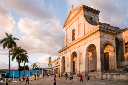 Trinidad, Cuba - 2012, December 8 : People walking in front of the colonial Holy Trinity cathedral glowing in the sunset in the main square of Trinidad, Cubaのeditorial素材