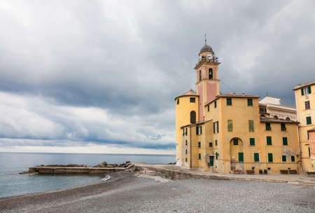 The church of Camogli on the pebble beach in front of the sea on a rainy cloudy day, Italy