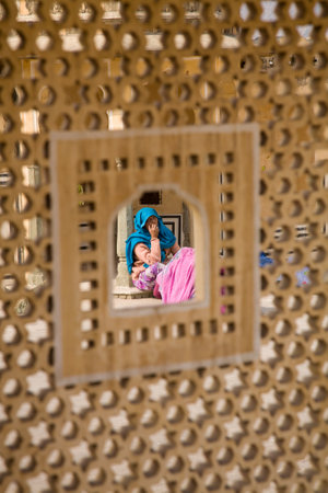 Jaipur, India - 2014, December 31 : A woman in traditional Rajasthani dress seen through an opening in a jali which is a typical latticed stone screen used in Indiaのeditorial素材