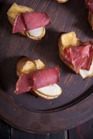 Bread Brie Cheese and Rolled Pastrami with Nuts and Honey on a Wooden Tray