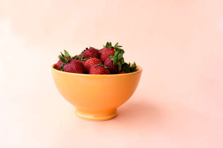 Fresh Stemmed Strawberries in an Orange Bowl. White Backgroundの写真素材