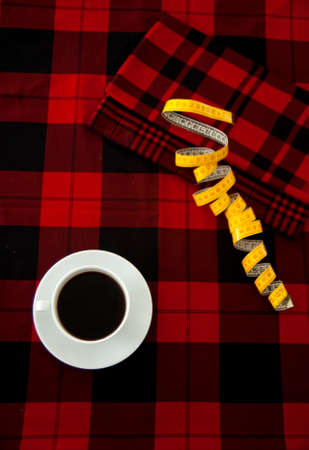 Cup of Coffee and Tape Measure on a Gingham Fabric Black and Redの写真素材
