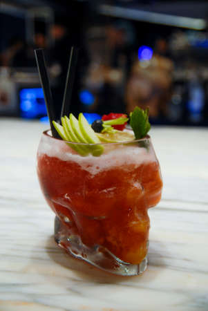 Red Cocktail with Fresh Mint Leaves, Green Apple Slices, Black Straws and Lime Wedge on a Marble Bar...