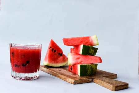 Watermelon Slice on a Wooden Cutting Board with Watermelon Juice on a Gray Background