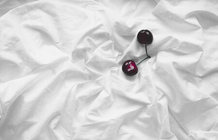 Top view of a cherry on a crumpled white background of bed linen.の写真素材
