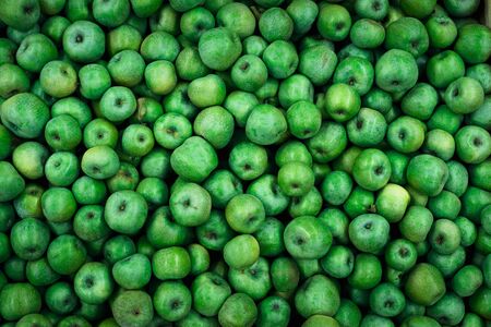 background of bright green apples on sale at the local marketの写真素材
