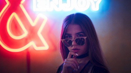 Girl in sunglasses on a neon background in the clubの写真素材