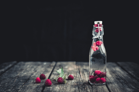 Bottle delicious refreshing drink of raspberry. Wood background.の写真素材