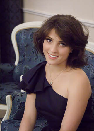 Upper body portait of beautiful natural young woman, sitting in an armchairの写真素材