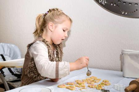 Little girl decorating cookies with suger sprinklesの写真素材