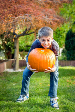Little boy holds a big pumpkinの写真素材
