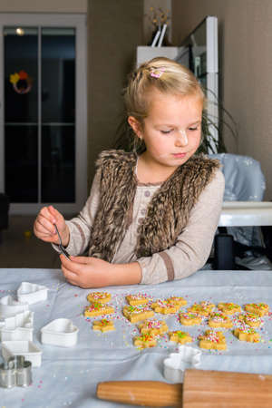 Little girl decorating cookies with sugar sprinklesの写真素材