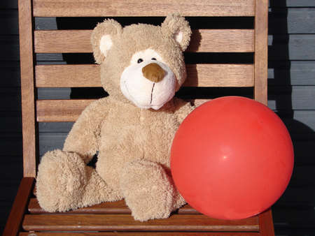                               Toy teddy bear holds a red balloonの写真素材
