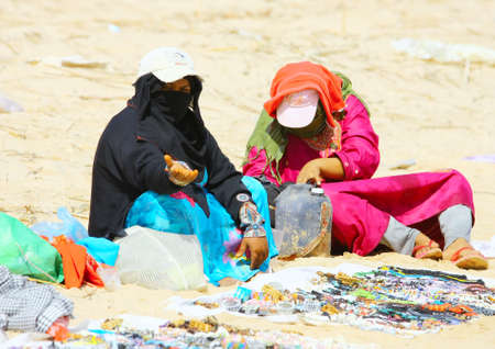 SHARM EL-SHEIKH, EGYPT, OCTOBER 15: Poor Arabian women wearing a head covering sit on the sand beach near the luxury hotelのeditorial素材