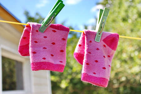 Pink baby sock hanging on the clothesline outdoor