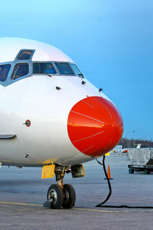 Closeup of red aircraft nose with pilot cabin against blue skyの写真素材