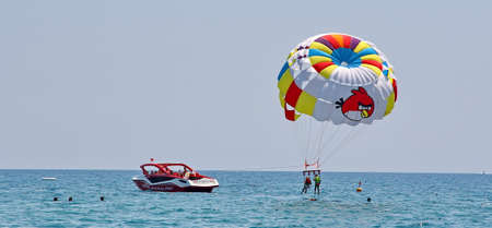 KEMER, TURKEY - AUGUST 14, 2015: Parasailing in a blue sky near sea beach. Parasailing is a popular recreational activity among tourists in Turkey.のeditorial素材