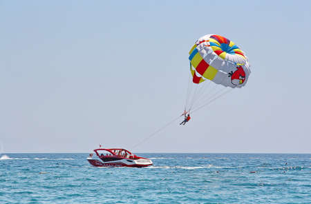 KEMER, TURKEY - AUGUST 14, 2015: Parasailing in a blue sky near sea beach. Parasailing is a popular recreational activity among tourists in Turkey.のeditorial素材