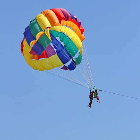 KEMER, TURKEY - AUGUST 18, 2015: Parasailing in a blue sky near sea beach. Parasailing is a popular recreational activity among tourists in Turkey.のeditorial素材
