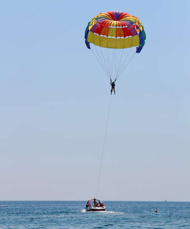 KEMER, TURKEY - AUGUST 18, 2015: Parasailing in a blue sky near sea beach. Parasailing is a popular recreational activity among tourists in Turkey.のeditorial素材