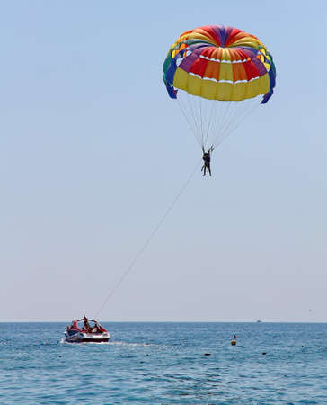 KEMER, TURKEY - AUGUST 18, 2015: Parasailing in a blue sky near sea beach. Parasailing is a popular recreational activity among tourists in Turkey.のeditorial素材