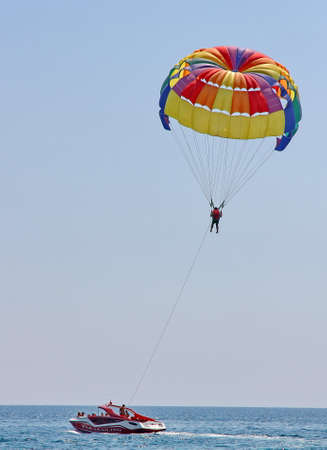 KEMER, TURKEY - AUGUST 18, 2015: Parasailing in a blue sky near sea beach. Parasailing is a popular recreational activity among tourists in Turkey.のeditorial素材