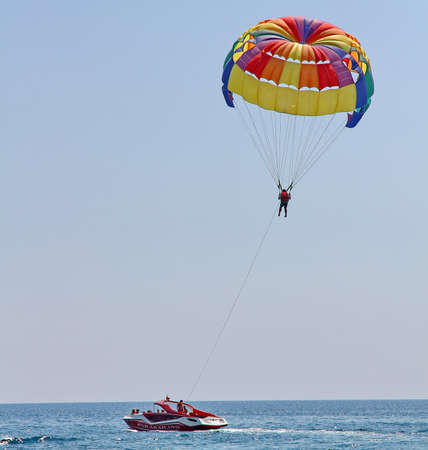 KEMER, TURKEY - AUGUST 18, 2015: Parasailing in a blue sky near sea beach. Parasailing is a popular recreational activity among tourists in Turkey.のeditorial素材
