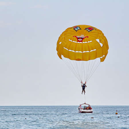 KEMER, TURKEY - AUGUST 16, 2015: Parasailing in a blue sky near sea beach. Parasailing is a popular recreational activity among tourists in Turkey.のeditorial素材