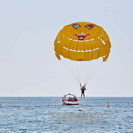 KEMER, TURKEY - AUGUST 16, 2015: Parasailing in a blue sky near sea beach. Parasailing is a popular recreational activity among tourists in Turkey.のeditorial素材