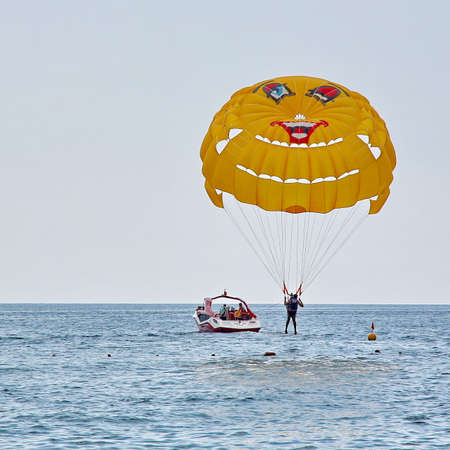 KEMER, TURKEY - AUGUST 16, 2015: Parasailing in a blue sky near sea beach. Parasailing is a popular recreational activity among tourists in Turkey.のeditorial素材