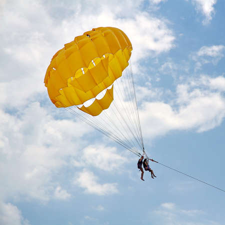 KEMER, TURKEY - AUGUST 16, 2015: Parasailing in a blue sky near sea beach. Parasailing is a popular recreational activity among tourists in Turkey.のeditorial素材