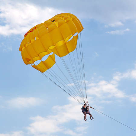 KEMER, TURKEY - AUGUST 16, 2015: Parasailing in a blue sky near sea beach. Parasailing is a popular recreational activity among tourists in Turkey.のeditorial素材