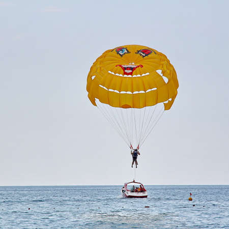 KEMER, TURKEY - AUGUST 16, 2015: Parasailing in a blue sky near sea beach. Parasailing is a popular recreational activity among tourists in Turkey.のeditorial素材
