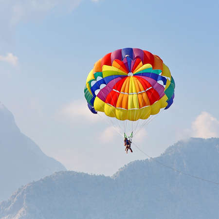 KEMER, TURKEY - AUGUST 18, 2015: Parasailing in a blue sky near sea beach. Parasailing is a popular recreational activity among tourists in Turkey.のeditorial素材