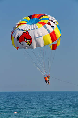 KEMER, TURKEY - AUGUST 12, 2015: Parasailing in a blue sky near sea beach. Parasailing is a popular recreational activity among tourists in Turkey.のeditorial素材