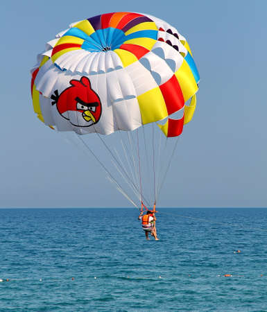 KEMER, TURKEY - AUGUST 12, 2015: Parasailing in a blue sky near sea beach. Parasailing is a popular recreational activity among tourists in Turkey.のeditorial素材